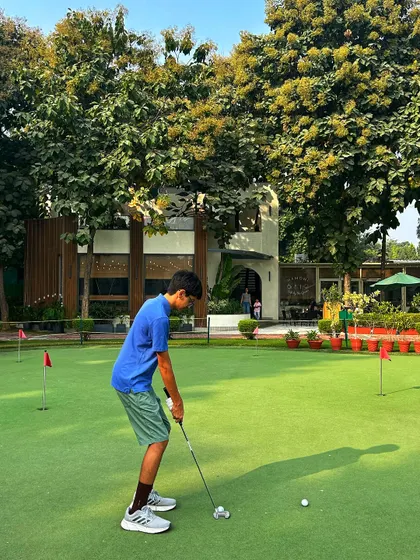 A young player focuses intently on his putt on our practice green. We provide a safe and encouraging space for kids to develop their skills.