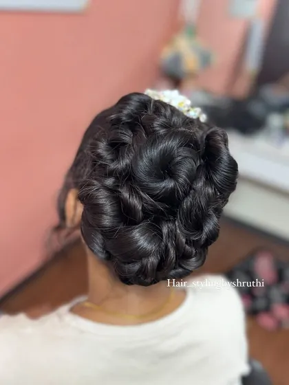 An intricate rose-petal bun, where sections of hair are sculpted to resemble blooming roses. This is a highly detailed and artistic updo, perfect for a bride who wants a unique hairstyle.