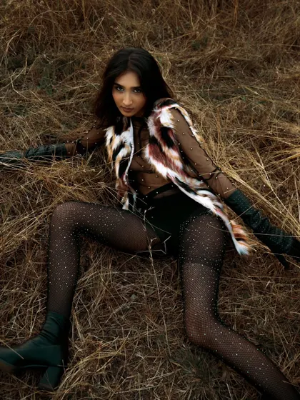 A dynamic and engaging pose from an outdoor fashion editorial. The model's connection with the camera is strong and confident.