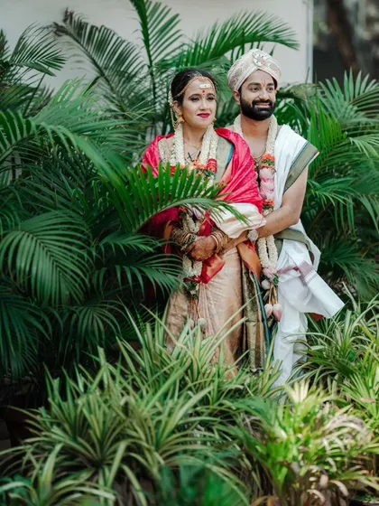 A classic wedding portrait of a couple standing amidst lush greenery.