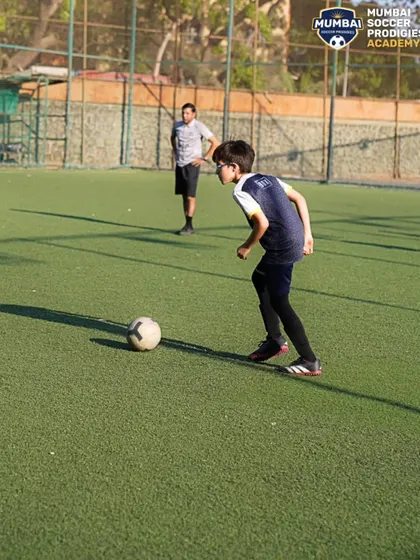 A young player prepares to strike the ball, learning the fundamentals of shooting.