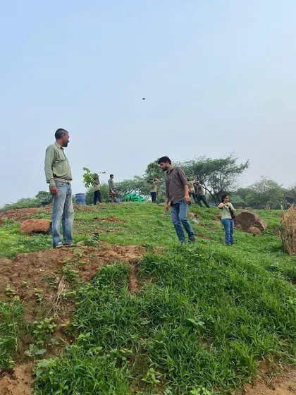 A view of the rocky, greening landscape at Aravali Nagar Van during a plantation drive, showing the challenging but rewarding nature of our work.