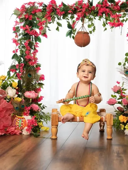 A full view of one of my Janmashtami setups, complete with a floral arch, peacock feathers, and a pot of butter.