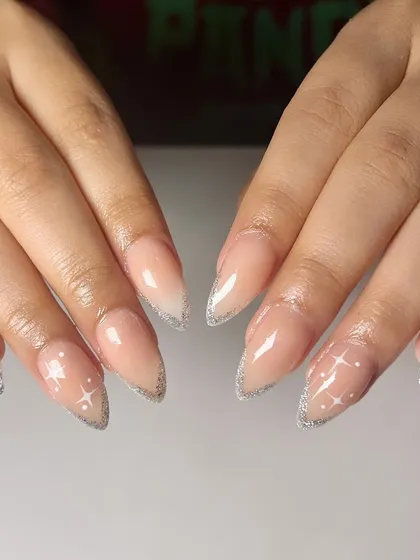 A magical twist on a classic. This set features glittery silver French tips, with delicate starbursts painted on the nail bed for a celestial, sparkling effect.
