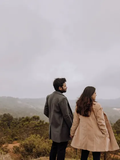 The couple holding hands and looking out at the vast, misty mountain range, symbolizing the start of their journey together.