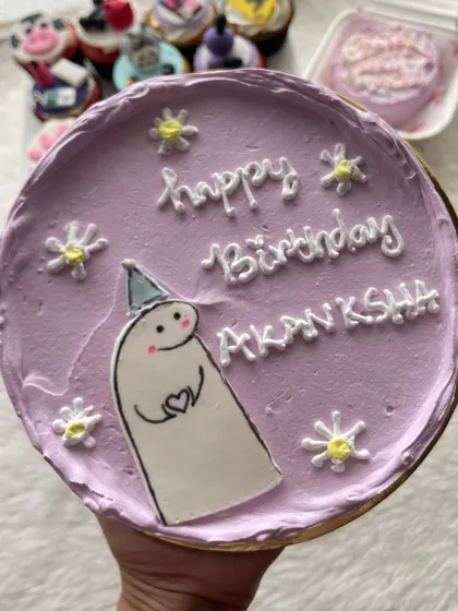 A cute character bento cake in a lovely lilac color, surrounded by little daisies.