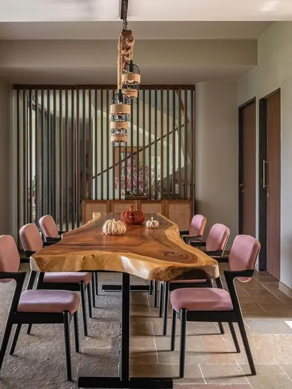 The dining area at Grove House features a stunning live-edge wooden table that seats a large group, perfect for family gatherings. The design combines rustic, natural elements with modern chairs and lighting to create a warm and inviting atmosphere.