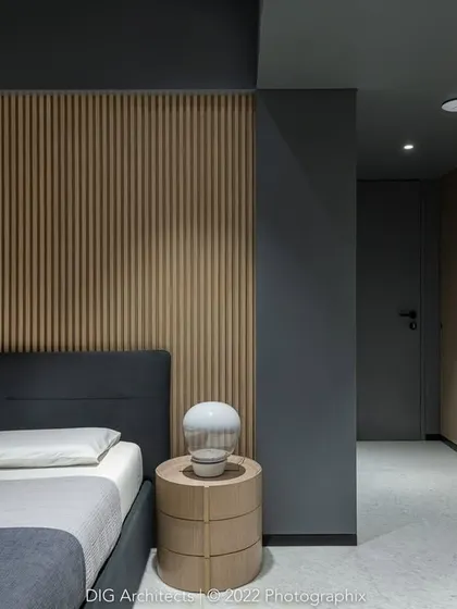 The second son's bedroom in 'A Hint of Azul'. A long, curving veneered wall guides you into the space, with a charcoal grey ceiling and black metal skirting framing this continuous wooden element.