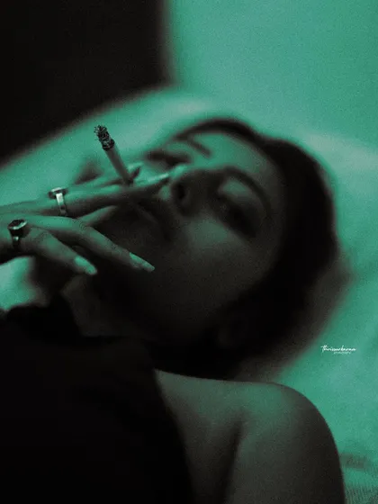 A dark and moody boudoir-style shot, using colored gels to create a dramatic, non-traditional look. The focus is on form and shadow.