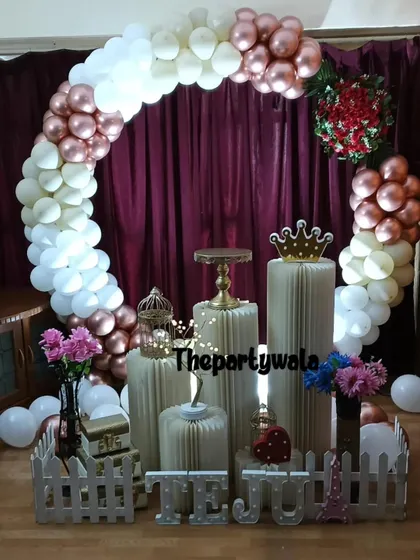 A rose gold and white balloon ring against a dark curtain, creating a dramatic effect.