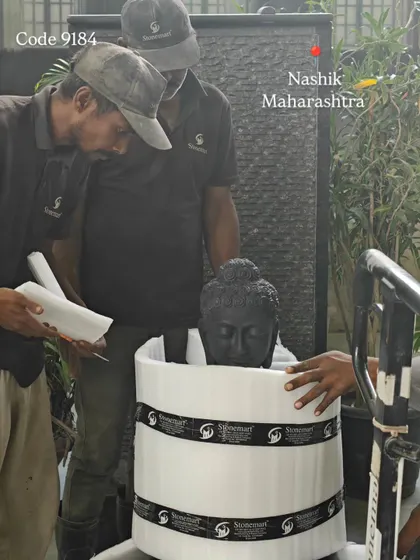 The careful process of wrapping a black marble Buddha head in protective foam before it is placed in its custom shipping crate.