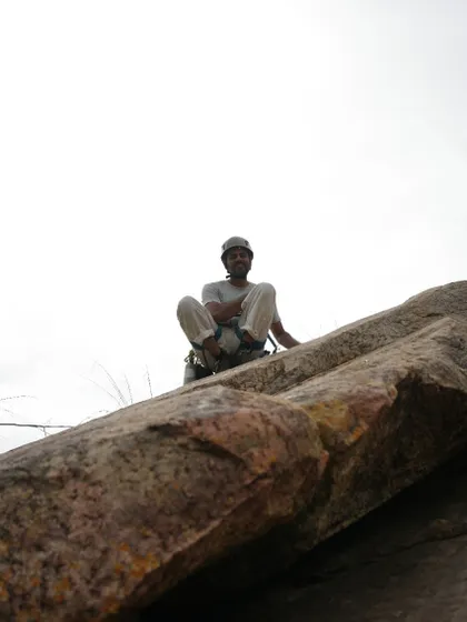 A climber smiles from the top of a rock, enjoying the feeling of accomplishment and the view. This is what it's all about.