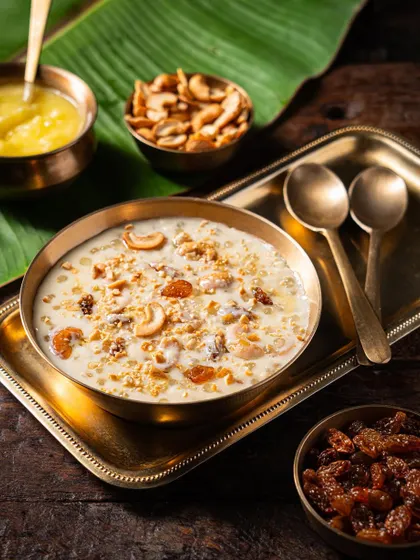 A close-up of a sweet pongal or payasam dessert in a brass bowl. The metallic props add a touch of elegance and authenticity.