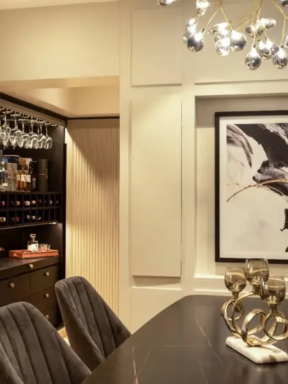 This dining and bar area in a 700 sq ft living space features a hidden bar, a detail I love for its space-saving functionality and surprise element. The black finish of the bar adds a touch of sophistication.