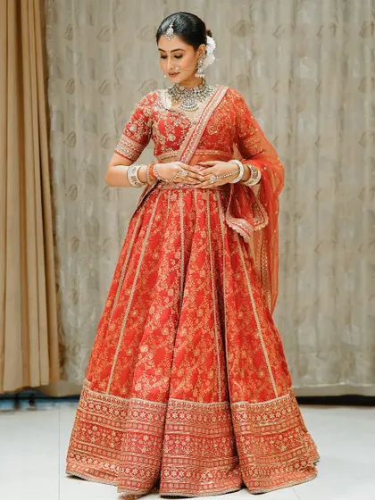 The complete bridal look is a vision of elegance. The rich red lehenga is perfectly complemented by a polished makeup look and a classic bridal updo.