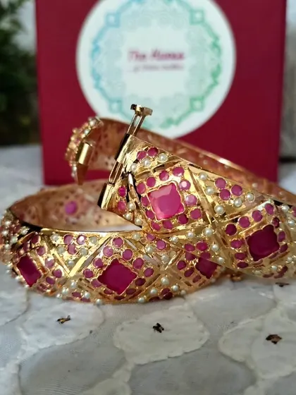The 'रानी' (Rani) gold-plated Jadau bangles. The ruby-red stones give these openable bangles a rich, royal look.