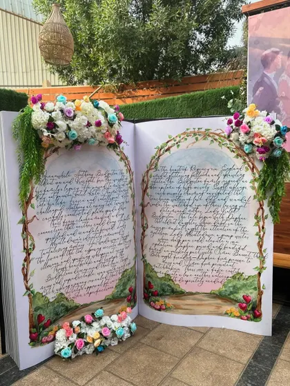 A truly unique photo opportunity: a giant, open storybook prop, adorned with flowers, perfect for a fairytale or Bridgerton-themed event.