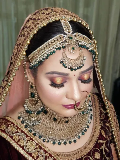 This is my signature bridal makeup style. It features a warm, sunset-toned halo eye, perfectly defined brows, and a flawless base. This look is paired with heavy emerald and gold jewelry for a truly royal effect.