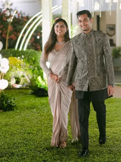 A grand entrance for the happy couple. They walk hand-in-hand through a garden path lined with modern, heart-shaped lights, a beautiful start to their elegant reception.