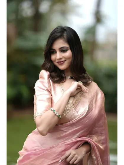 A portrait shot capturing the soft, romantic feel of the pink tissue silk saree.