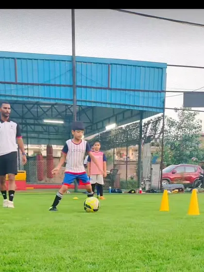 A young player practices dribbling under the watchful eye of his coach. This personalized attention helps each child improve at their own pace.