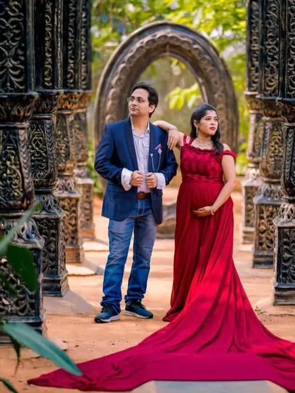 A walking pose that shows the length and flow of the red trail gown. This is a perfect choice for couples who want a touch of glamour and drama in their pre-wedding or maternity photos.