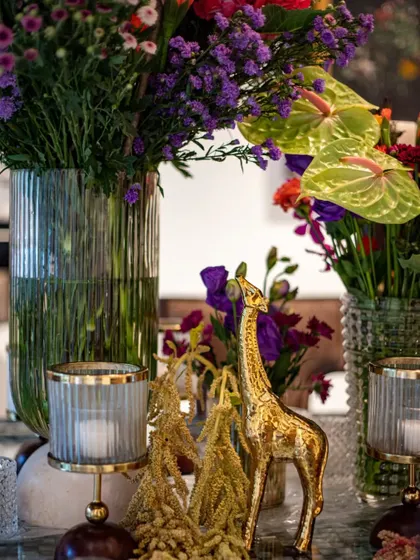 A close-up of another golden giraffe figurine amidst the lush florals. These recurring motifs help to tie the entire decor scheme together.