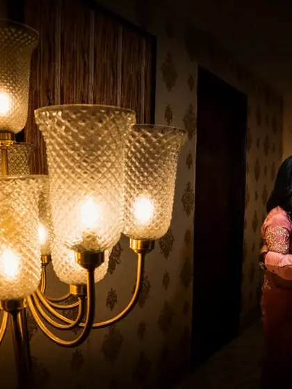 In the quiet corners, away from the crowd, are where the most intimate moments happen. The warm glow of the chandelier highlights a tender forehead kiss, a silent promise between the couple.