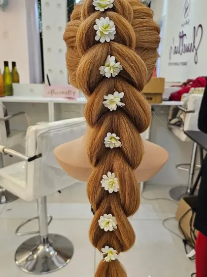 A stunning pull-through braid decorated with small white flowers, created on a mannequin during a practice session.