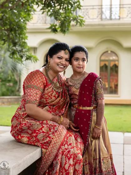 A lovely portrait of a mother and daughter dressed in beautiful traditional sarees for a family ceremony. Their shared smile captures a beautiful family bond.