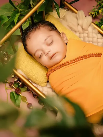 A beautifully framed close-up of the baby during the "Jai Shree Ram" shoot, capturing a peaceful moment amidst the greenery.