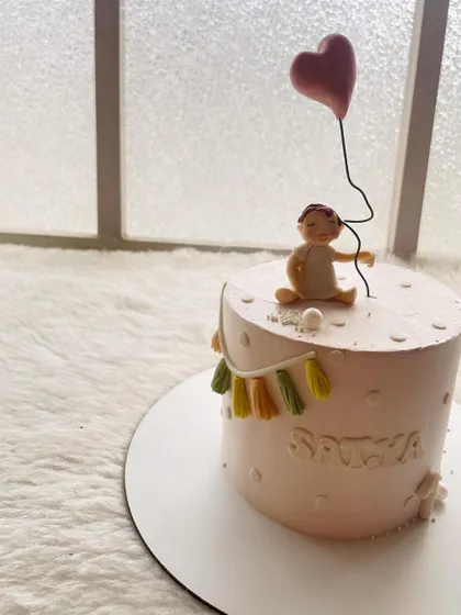 A simple and sweet cake for a first birthday. The design features a baby holding a balloon, with soft colors and delicate details.