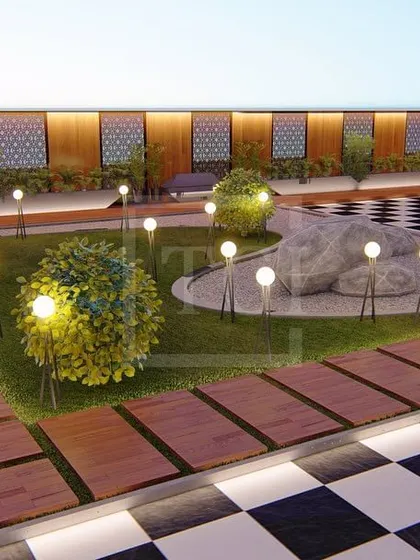 A close-up of the garden area in the Gurgaon project, with a wooden pathway, globe lights, and a large rock installation.