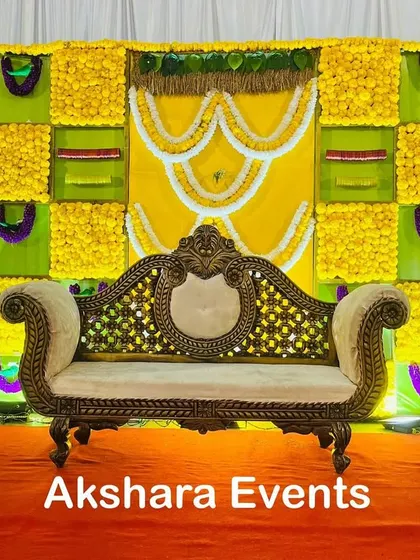 A classic yellow and green themed backdrop for a Seemantham ceremony. The design uses panels of marigolds and is decorated with garlands of white flowers in a traditional pattern.