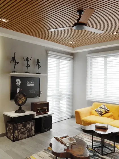 Each piece of furniture in the Grey Apartment was custom-designed. The brown-paneled ceiling offers a rich contrast to the grey-toned flooring, adding depth and visual intrigue to this cozy living space.