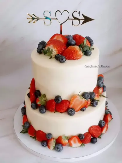 For a fresh and rustic feel, this two-tier wedding cake is adorned with fresh strawberries and blueberries. The custom initial topper adds a personal touch to this simple, no-fondant design.