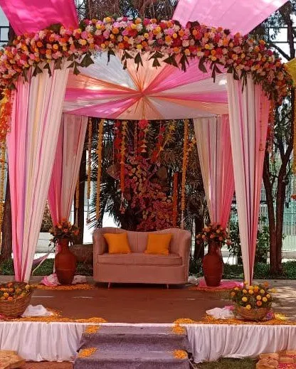 A full view of the pink and yellow draped stage, perfect for a daytime pre-wedding celebration.