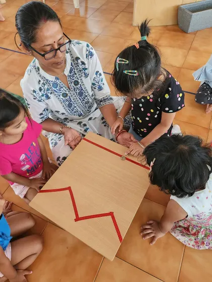 A teacher guides children in a sensorial activity during summer camp. We continue our hands-on learning approach with fun, summer-themed projects.