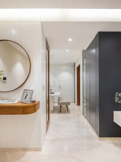 Another perspective of the entryway, highlighting the clean lines and the interplay between the white fluted panels, dark grey wall, and warm wood furniture.