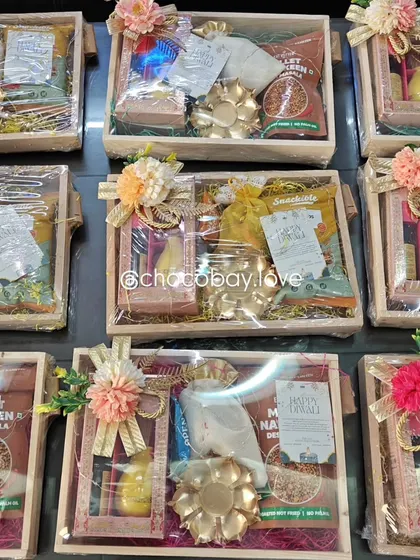 A closer look at the versatile wooden gift hampers without the decorative lighting. You can see the variety of contents, including snack packets, chocolate boxes, and small decorative items.