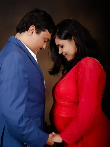 An intimate moment between expecting parents during their indoor maternity shoot. We provide outfits for both mom and dad-to-be.