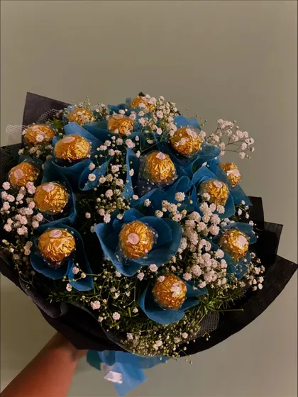 A cool and sophisticated chocolate bouquet. Here, Ferrero Rocher chocolates are wrapped in a beautiful shade of blue and mixed with baby's breath for a fresh and unique look.
