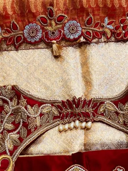 The back of the blouse, showing how the floral embroidery and pearl details come together. The central pearl tassel is a key focal point.