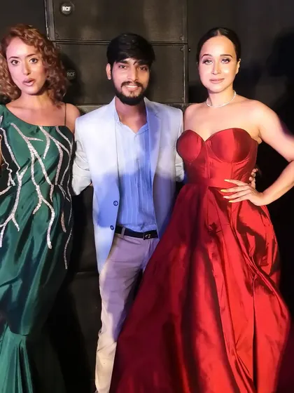A backstage moment from the fashion show with two of the models wearing my custom gowns. One is in the classic red ball gown, and the other wears a green mermaid gown with unique applique work.