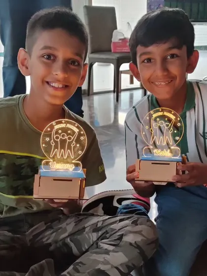 Two friends show off the matching light-up trophies they built and customized. It's a fantastic take-home item that reminds them of their achievement.