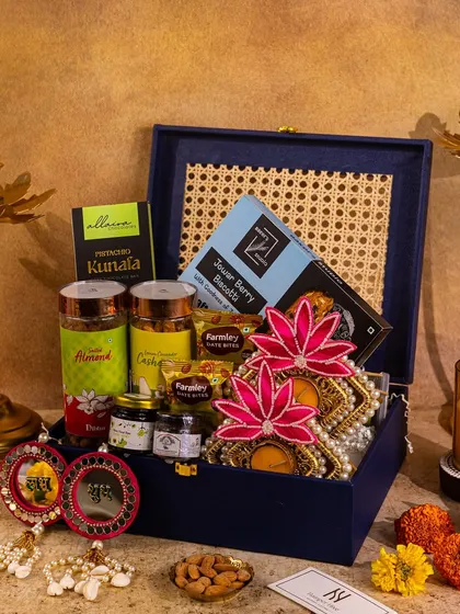 This shot highlights a navy blue hamper with cane detailing, surrounded by the warm glow of candles for a sophisticated festive look.