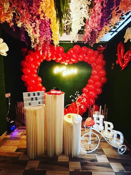 A full view of 'The Green Dream' decor, with a heart-shaped red balloon arch against a green wall, perfect for birthdays and anniversaries.