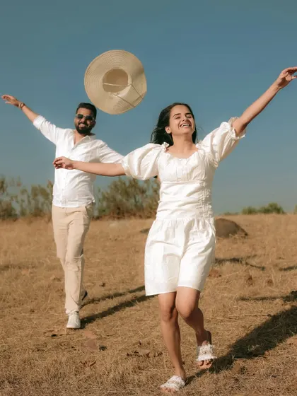A joyful, high-energy shot in an open field, capturing the couple's happiness and excitement.