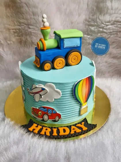 All aboard the birthday express! This cake features a sculpted fondant train engine on top, with a car, plane, and hot air balloon around the sides, perfect for a child fascinated by vehicles.