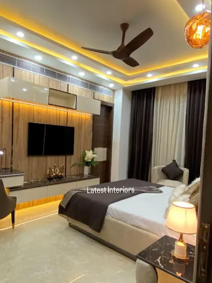A wider view of the master bedroom, showing the TV panel with wooden accents and the overall warm and inviting color palette.